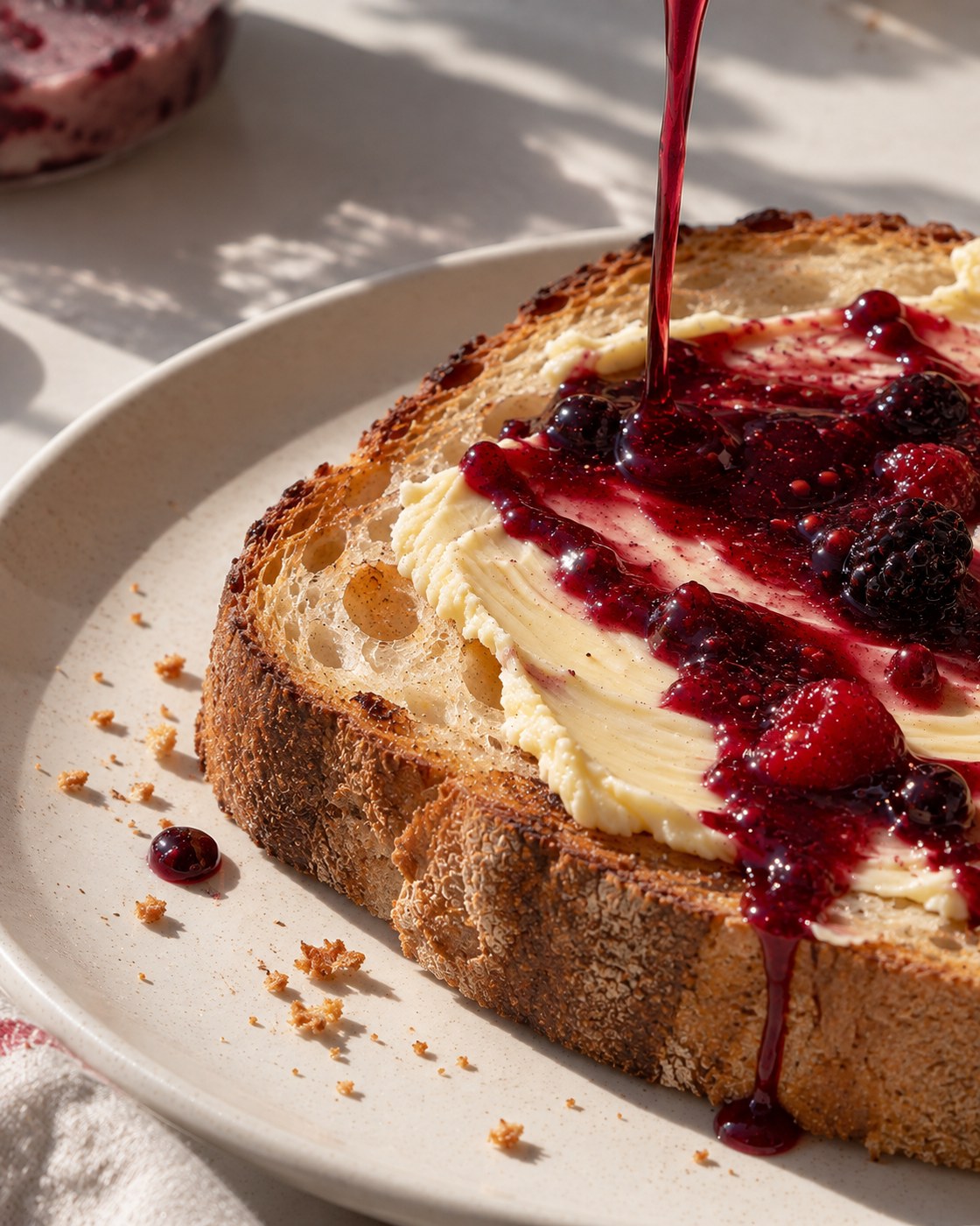 Berry syrup poured over toast spread with butter and fresh berries