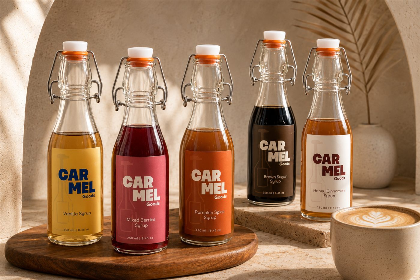 Five CARMEL Goods syrup bottles arranged on a wooden board beneath a sunlit archway